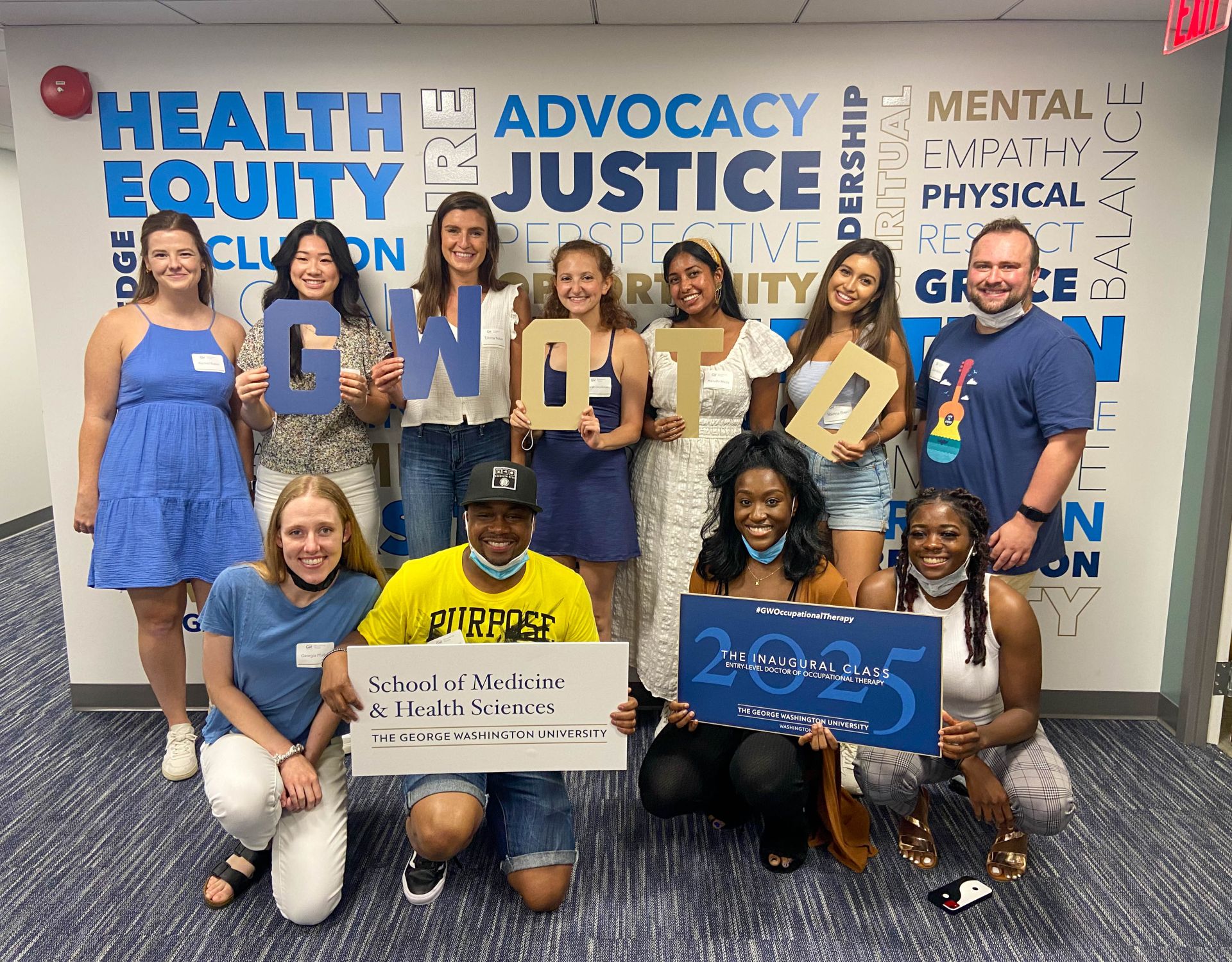 eOTD Students holding signs saying GW OTD, School of Medicine and Health Sciences, and The Inaugural Class