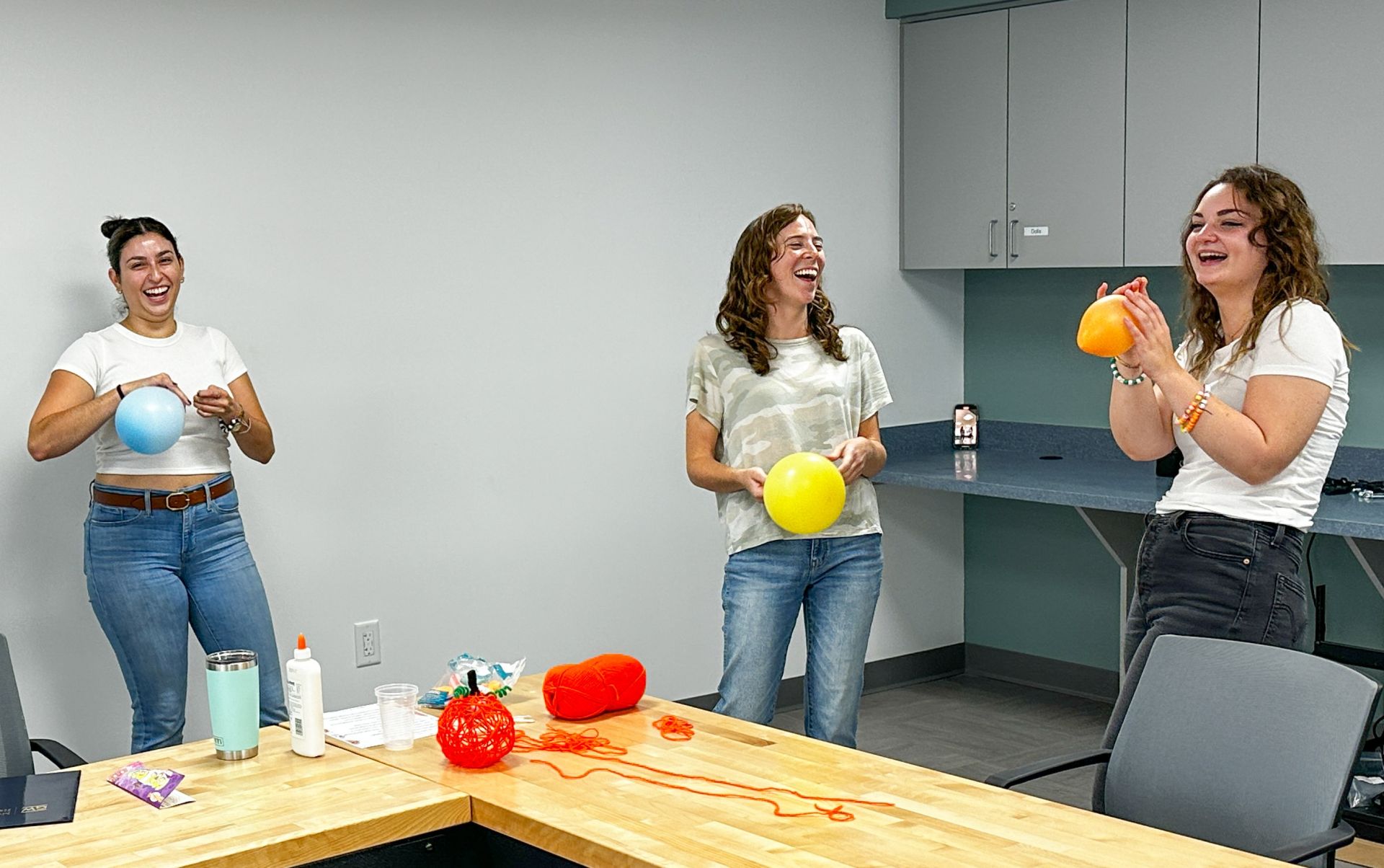 Three Students Blowing Up Balloons