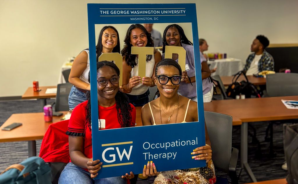GW OT Students in Blue Picture Frame Prop holding OTD gold letters
