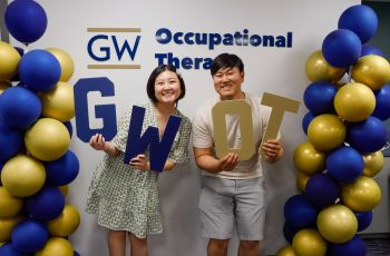 Two students holding GW OT Signs